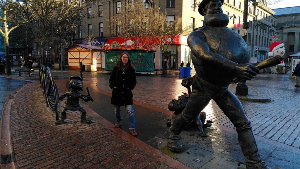 Clare posing between statues of Desperate Dan and Minnie the Minx