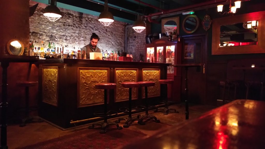 Barman behind speak easy bar with empty bar stools 