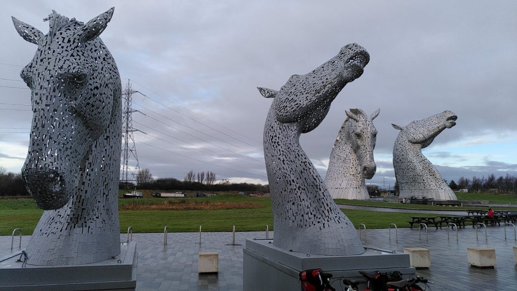 Small kelpie models in the foreground with the giant Kelpies in the background  appearing smaller than the models.