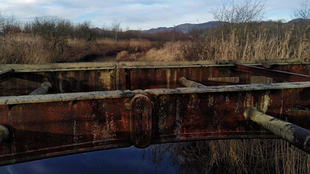 Rusty bridge in the foreground with distant hills behind