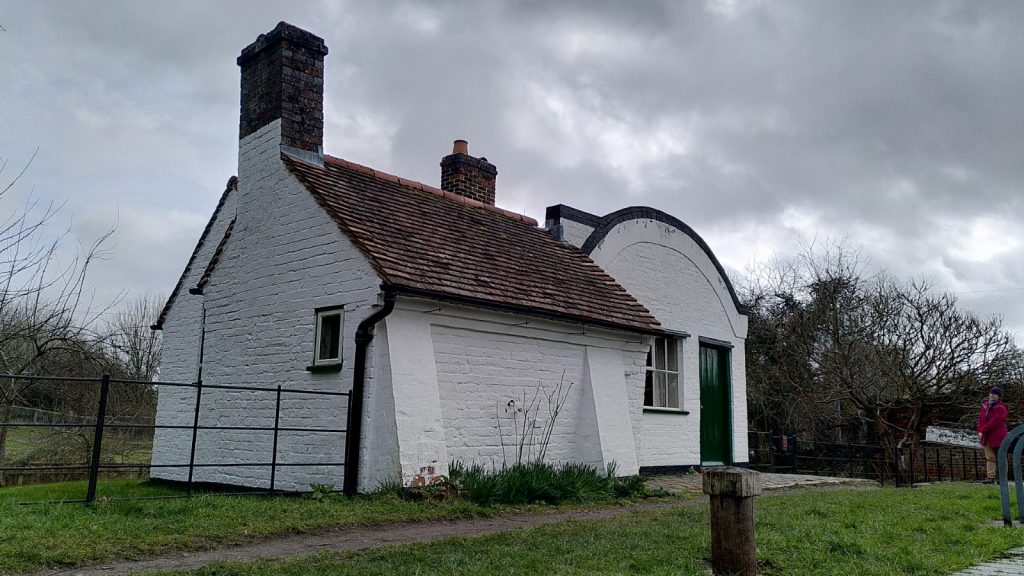Extended lockman's cottage.  The section with the barrel-shaped roof has had a more traditional square cottage with tiled roof built alongside.  Both are painted white.