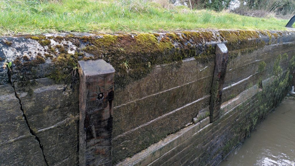 The inside wall of a lock shows an abrupt horizontal displacement of a few inches.  Two vertical bumpers force boats to keep away from the edge at this point.