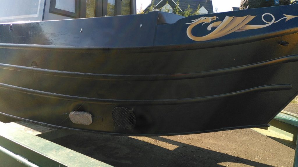 Bow of a narrowboat out of water.  Just visible is a grill covering the the thruster tube.  An anode is the only unpainted part of the lower hull.