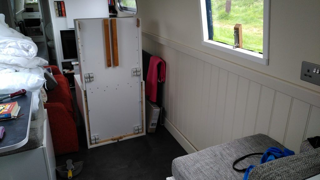 Inside a narrowboat with built-in furniture in disarray.