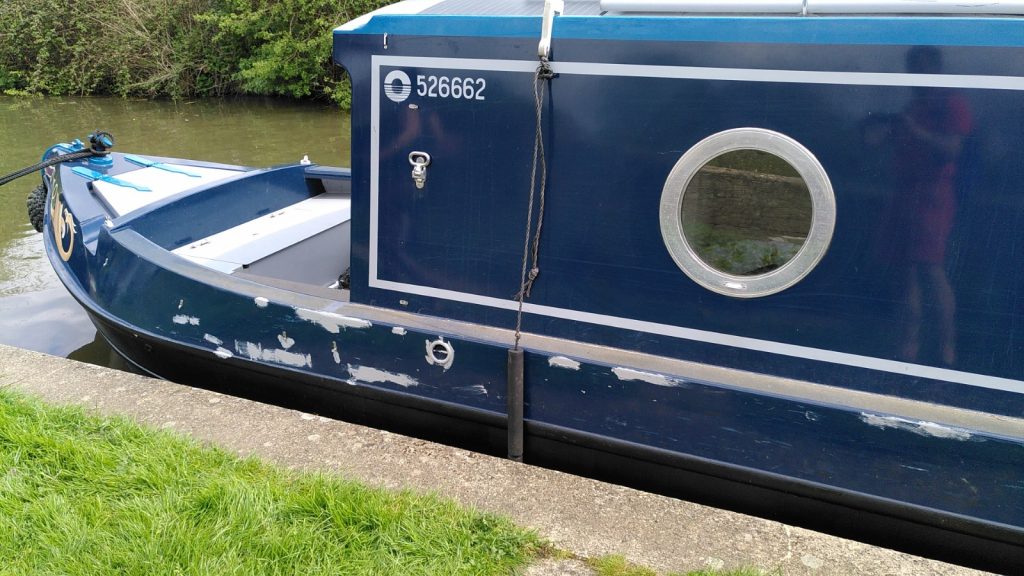 Front of a narrowboat with large amounts of primer on the paintwork below the gunwale.