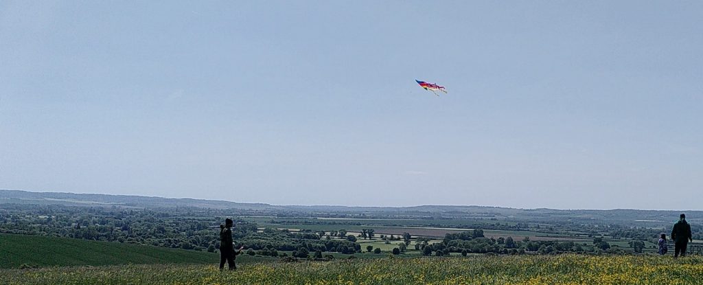 View over surrounding countryside from the top of Castle Hill.  Somebody is flying a kite - the main colour visible is red.