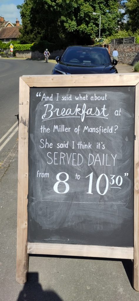 A blackboard outside a pub saying "AndI said what about Breakfast at th Miller of Mansfield? She said I think it's served daily from 8 to 10.30"