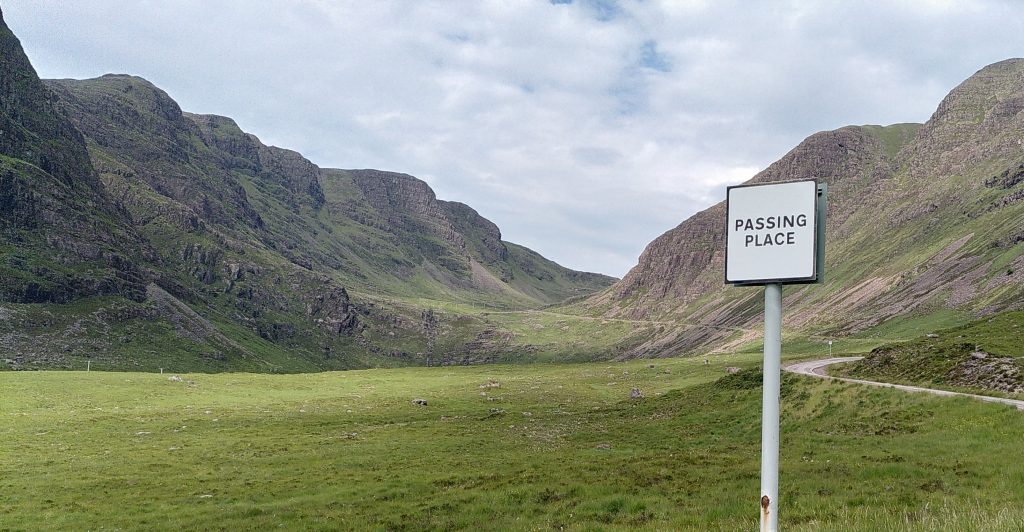 Looking towards a notch between two large mountains. A sign in the foreground says "Passing Place".