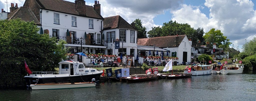 Riverside pub "The Swan"  with a collection of swan upping boats moored outside.