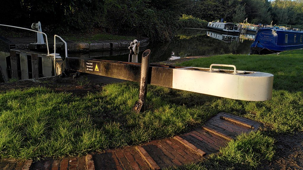 A lock gate arm in the evening sunshine.  A bollard is in place to stop the gate from being opened.