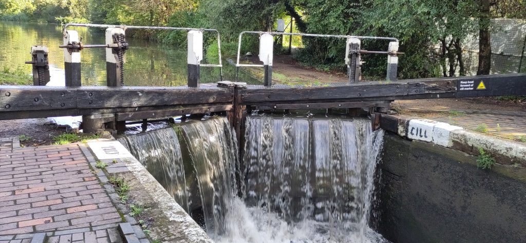 Water cascading over lock gates.  There is a walkway and step above water level.