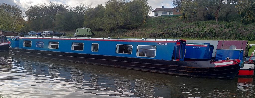 Moored narrowboat.  This is part of a large fleet with a distinctive livery.  This is one of the longest with a large open front deck.  It is called "Kingfisher".