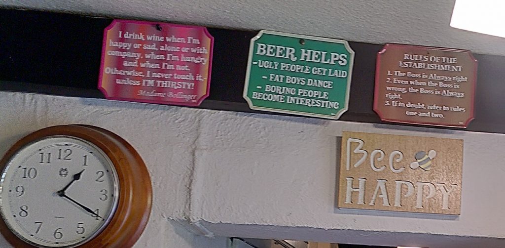 Signs above the bar.  A group of "comic" signs above the bar.  The largest sign simply says "Bee Happy" with a picture of a bee.