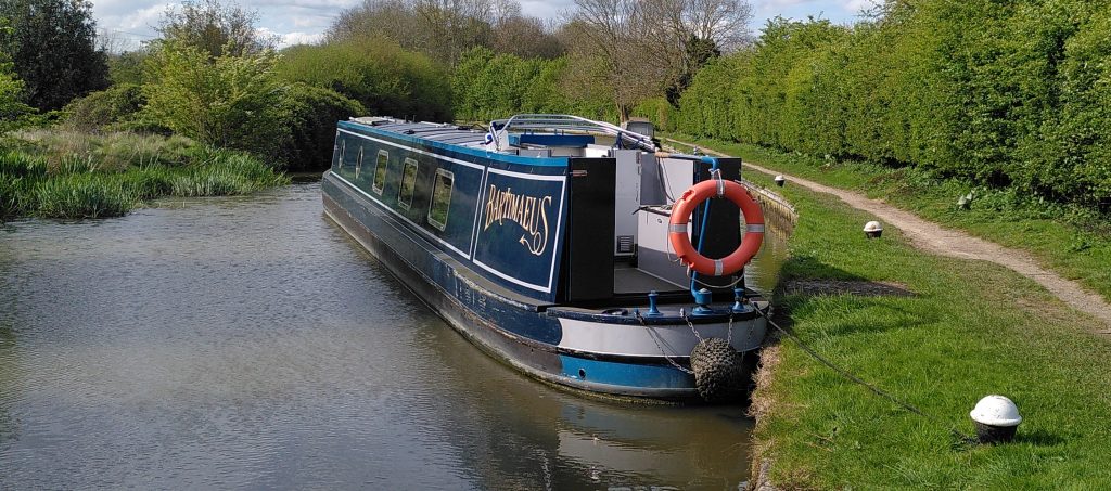 On a Strop.  A narrowboat sits at the side of a canal.  I short length of rope -  a strop - ties it to a bollard at the stern. 