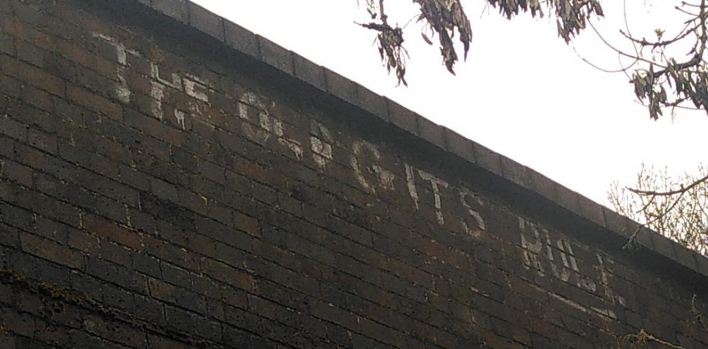 Bridge graffiti.  A brick canal bridge with words sprayed in white paint on the dark brick background.  The message is "THE OLD GITS RULE".