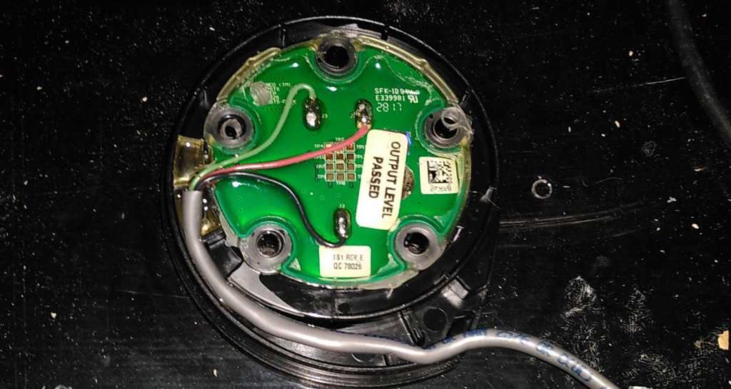 Tank sensor.  A circular circuit board with a cable bringing three wires to it.  The board has five holes for bolts around its circumference, and several labels on it.