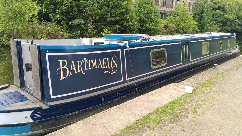 Painted.  A narrowboat is moored against a low concrete bank.  There are no patches of undercoat visible - the painting appears complete.