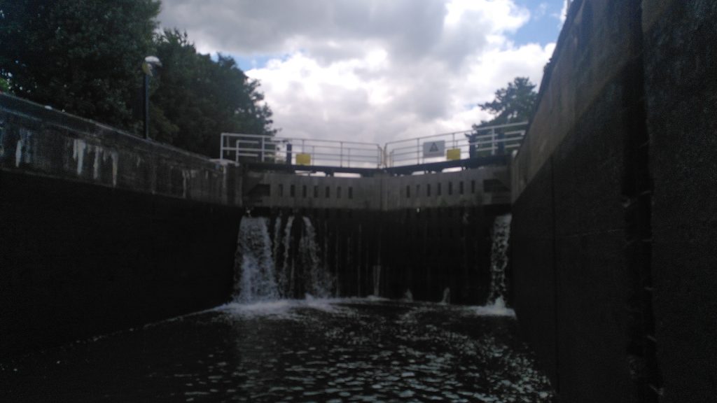 Holme Lock.  The top gates of a lock tower above the lock chamber as viewed from a boat inside.  The rear wall below the lock gates is significantly higher than the gates themselves, and much wider than it is high.